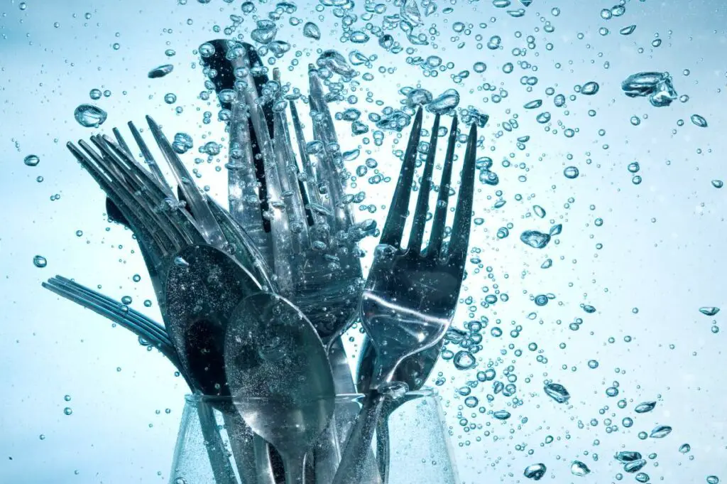 cutlery surrounded by water in a portable dishwasher symbolizing the water usage