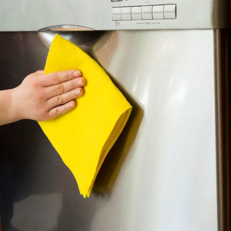 hand with cleaning rag cleaning exterior of dishwasher