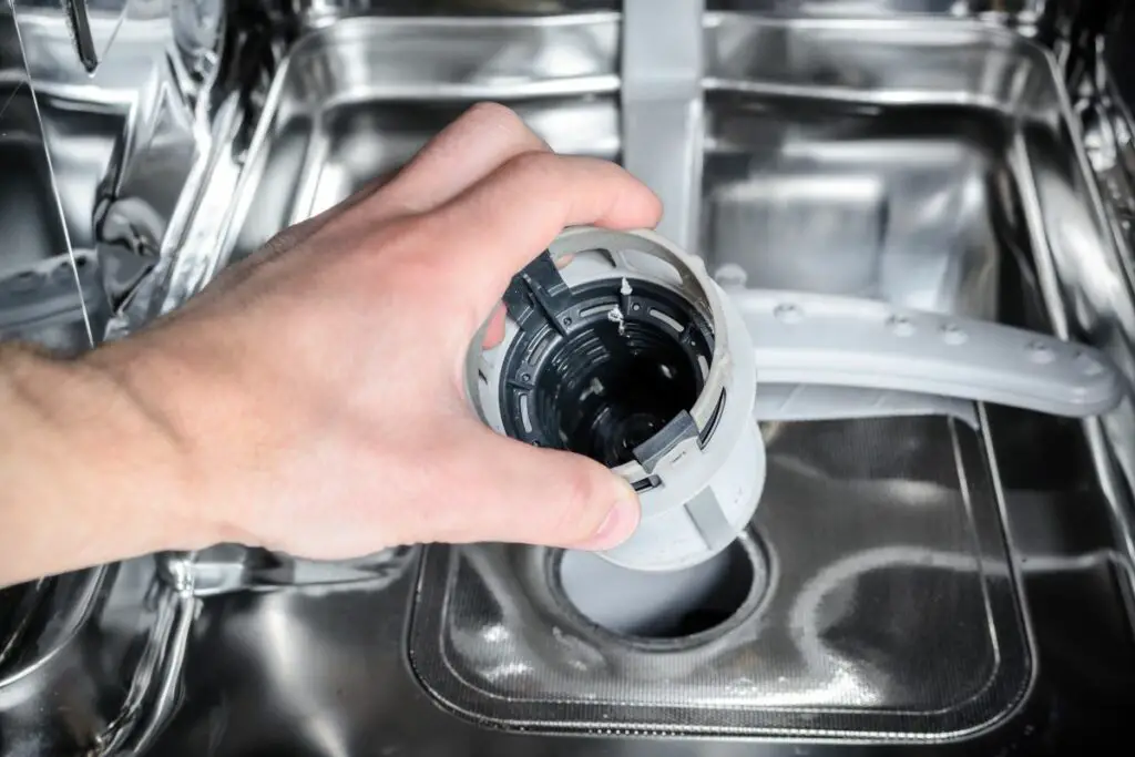 hand removing the filter from a dishwasher